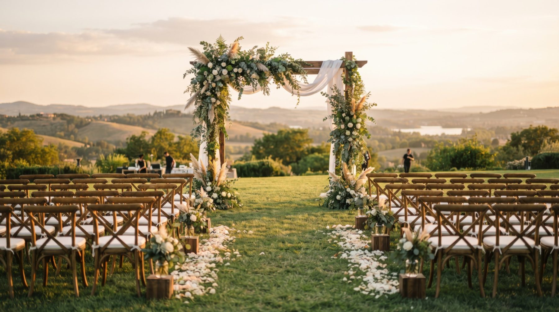 An outdoor ceremony with a floral arch and wooden chairs overlooking rolling hills at Wren Hollow Estate